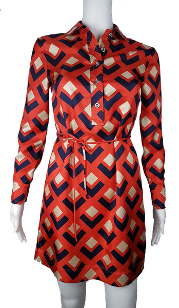 Full front view: a mannequin displaying a Banana Republic Madmen Collection silk red and navy geometric print shirt shift dress with a 5 button front bodice closure and matching string belt.