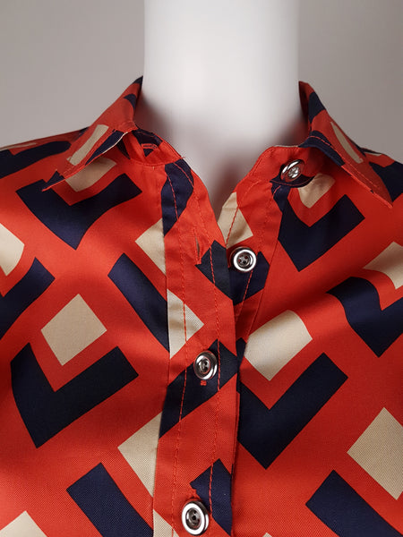 front collar and closure view: a mannequin displaying a Banana Republic Madmen Collection silk red and navy geometric print shirt shift dress with a 5 button front bodice closure and matching string belt.