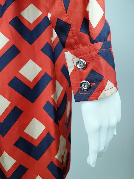 sleeve and cuff view: a mannequin displaying a Banana Republic Madmen Collection silk red and navy geometric print shirt shift dress with a 5 button front bodice closure and matching string belt.