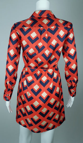 Full back view: a mannequin displaying a Banana Republic Madmen Collection silk red and navy geometric print shirt shift dress with a 5 button front bodice closure and matching string belt.