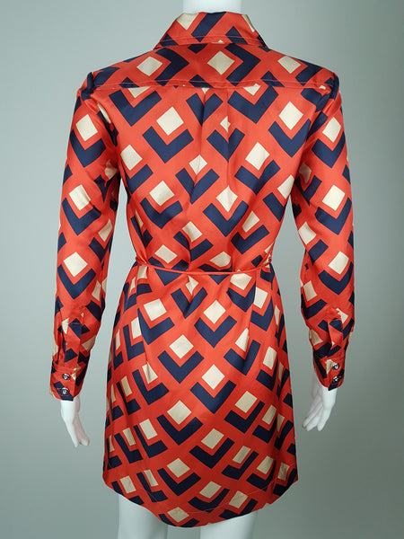 Full back view: a mannequin displaying a Banana Republic Madmen Collection silk red and navy geometric print shirt shift dress with a 5 button front bodice closure and matching string belt.