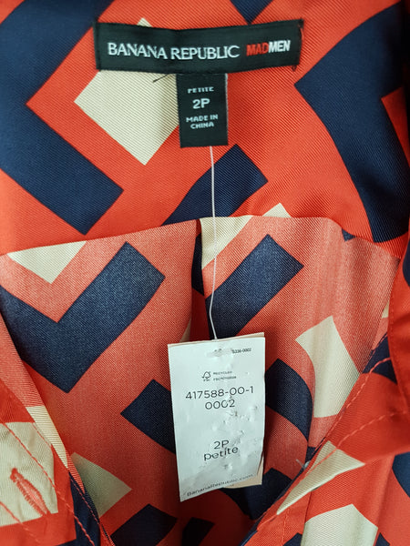 label view with original tag: a mannequin displaying a Banana Republic Madmen Collection silk red and navy geometric print shirt shift dress with a 5 button front bodice closure and matching string belt.