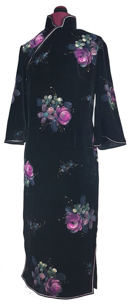Front view of a 1950s black velvet cheongsam qipao dress with a mandarin collar, contrasting piping and hand-painted pink floral design displayed on a mannequin 