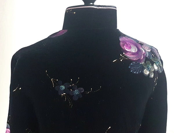 Back collar view of a 1950s black velvet cheongsam qipao dress with a mandarin collar, contrasting piping and hand-painted pink floral design displayed on a mannequin 