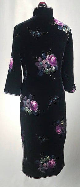 Back view of a 1950s black velvet cheongsam qipao dress with a mandarin collar, contrasting piping and hand-painted pink floral design displayed on a mannequin 