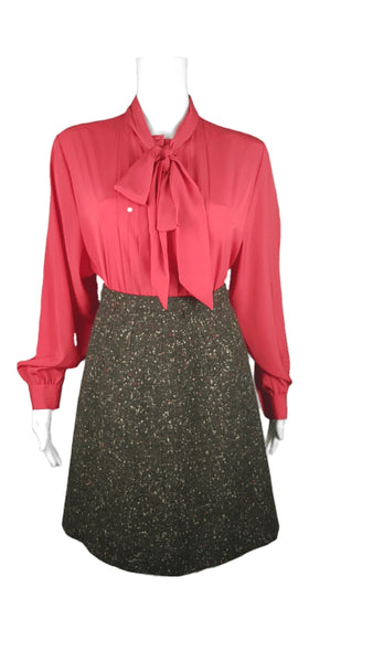 Vintage 1960s dark green confetti bouclé A-line skirt styled with a coral red bow blouse on a mannequin to show the silhouette.