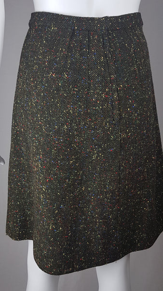 Vintage 1960s dark green bouclé A-line skirt with colorful confetti flecks in red, yellow, blue, and green, shown on a mannequin against a neutral background.