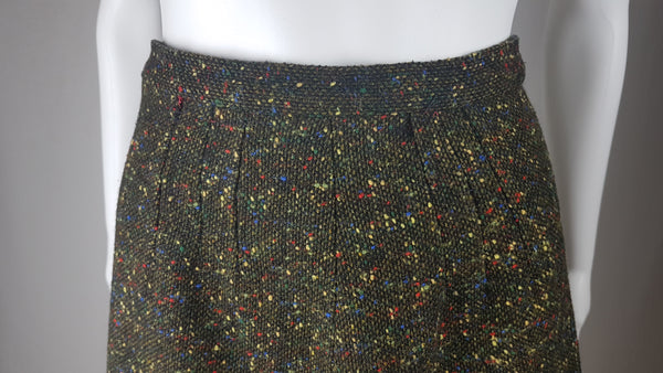Vintage 1960s dark green bouclé A-line skirt with colorful confetti flecks in red, yellow, blue, and green, shown on a mannequin against a neutral background.
