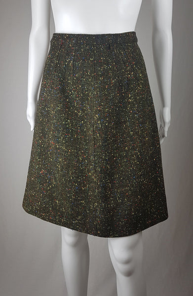 Vintage 1960s dark green bouclé A-line skirt with colorful confetti flecks in red, yellow, blue, and green, shown on a mannequin against a neutral background.