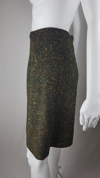 Vintage 1960s dark green bouclé A-line skirt with colorful confetti flecks in red, yellow, blue, and green, shown on a mannequin against a neutral background.