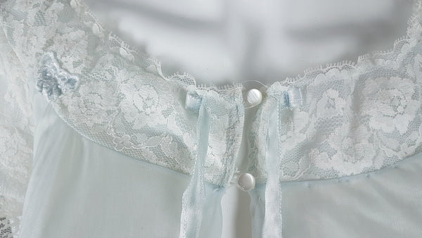 Button closure closeup of Vintage 1960s Aristocraft by Superior pastel blue peignoir with cream floral lace and ribbon ties displayed on a mannequin