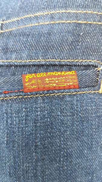 Close-up of the red-and-gold 7 For All Mankind label attached to the rear welt pocket of on 7 For All Mankind indigo jeans