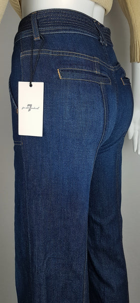 Closeup back view of deadstock tags on a 7 For All Mankind indigo palazzo jeans with a knotted denim belt, large patch pockets and wide legs displayed on a mannequin