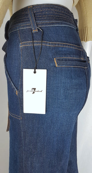 Closeup side view of deadstock tags on a 7 For All Mankind indigo palazzo jeans with a knotted denim belt, large patch pockets and wide legs displayed on a mannequin