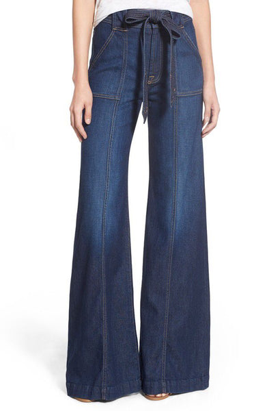 Studio model view of 7 For All Mankind Saint Tropez Night palazzo jeans with a matching tie belt and floor-skimming wide legs.