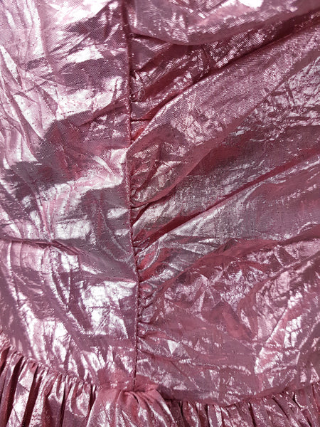 Close-up of metallic pink lamé fabric and visible surface wear near the waist