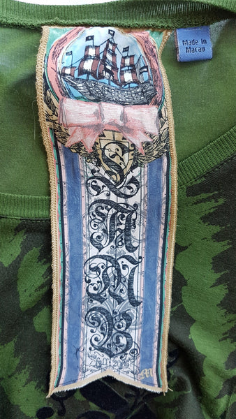 Label detail of Green and black patterned “LOVE” T-shirt top from Gwen Stefani’s Fall 2005 L.A.M.B. collection, with an ornate black chest motif.