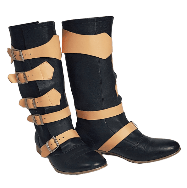 Three quarter view of a pair of black mid-calf leather boots wrapped with contrasting tan straps and antiqued metal buckles