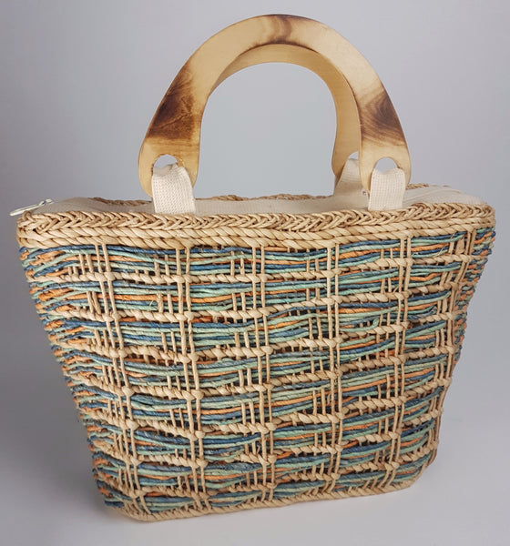 Front view of the large woven tote showing muted blue, green and coral strands beneath the natural weave