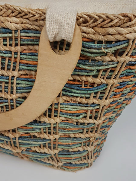 Close-up of a wooden handle attached through a cream woven tab at the top of the bag