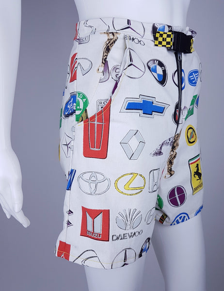 Three quarter view of high-waisted automotive-print shorts with an exposed metal zipper and checkerboard buckle belt