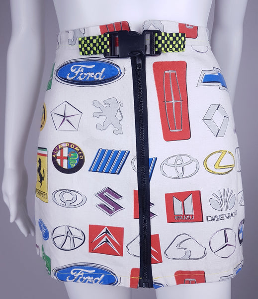 Front view of an automotive-logo mini skirt with a full-length exposed zipper and neon checkerboard belt
