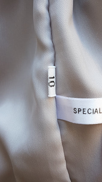 Size label on Saga Fox Pale blue fox fur jacket with long sleeves, a plush collar, and natural silver grey markings on a mannequin