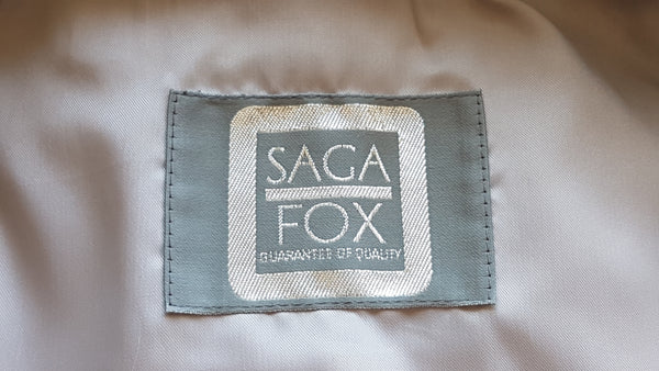 Brand label of Saga Fox Pale blue fox fur jacket with long sleeves, a plush collar, and natural silver grey markings on a mannequin