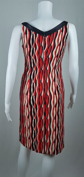 back view of a modern Tocca red, black and ivory Op Art woven sheath dress with black V-neck trim displayed on a mannequin