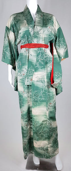 Full front view of a vintage 1940s green and cream floral silk kimono styled closed with a red scarf sash.