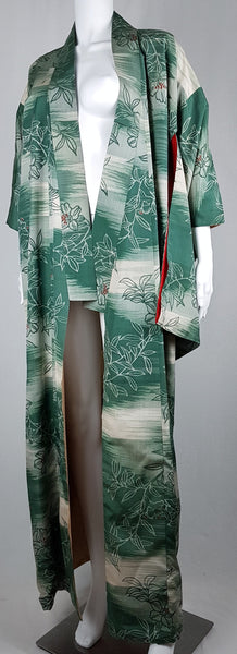 Full front view of a vintage Japanese green floral silk kimono worn open, showing its long straight panels and cream lining.