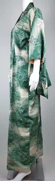 Side view of a full-length green silk kimono with wide three-quarter sleeves and an ivory botanical pattern.