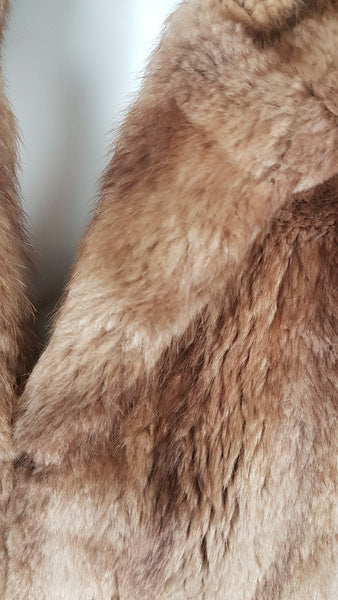 Close-up of the dense warm light-brown mink fur showing its soft guard hairs and natural tonal variation across the collar and chest.