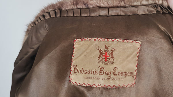 Close-up of the woven 1950s Hudson’s Bay Company label, mocha satin lining and pleated trim inside the vintage mink stole jacket.