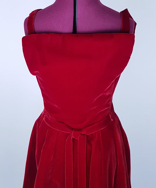 Front bodice view of a circa mid-1950s Suzy Perette dark red velvet dress with square neckline, narrow straps and full skirt displayed on a mannequin 