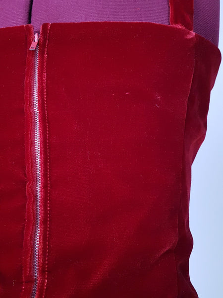 Front view of a circa mid-1950s Suzy Perette dark red velvet dress with fitted bodice, pleated skirt and long velvet waist ties.
