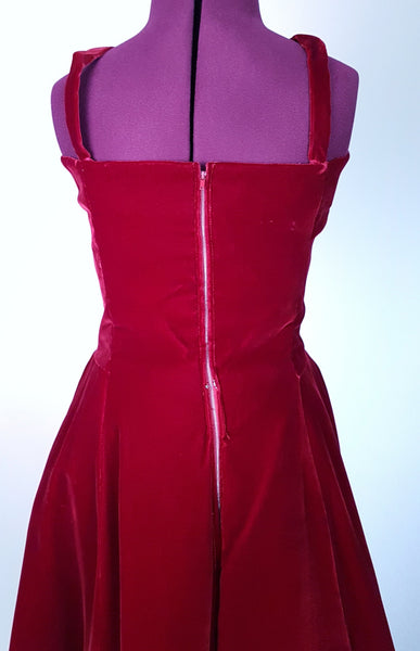 Back view of a circa mid-1950s Suzy Perette dark red velvet dress with fitted bodice, pleated skirt and velvet waist ties displayed on a mannequin 