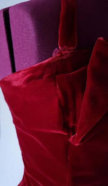 Closeup Side bodice view of a circa mid-1950s Suzy Perette dark red velvet dress with square neckline, narrow straps and full skirt displayed on a mannequin 