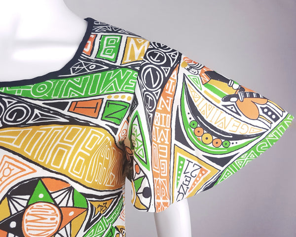 Close-up front shoulder view of a 1960s Gemini zodiac print dress, showing the scoop neckline and flared butterfly sleeve, displayed on a mannequin