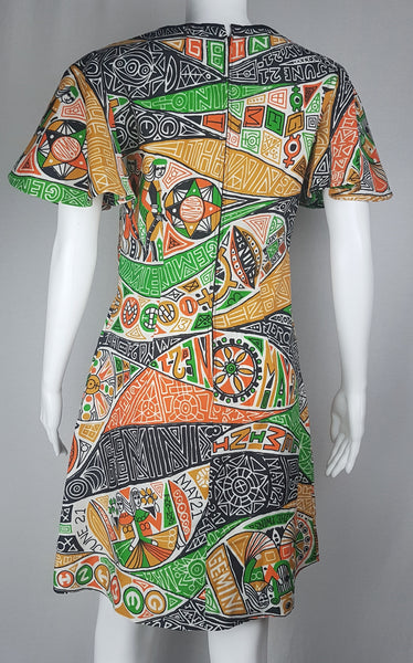 Back view of a 1960s Gemini zodiac novelty print shift dress with short butterfly sleeves and a colourful graphic design displayed on a mannequin 