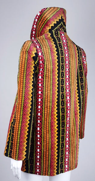Full three quarter back view of a vintage 1960s Trego’s Westwear chenille coat with a raised funnel collar, colourful geometric stripes and angled pockets displayed on a mannequin 