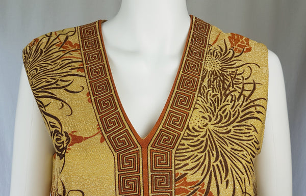 Closer front view of a gold metallic Alfred Shaheen maxi dress with a Greek-key-trimmed V-neckline and centre panel.
