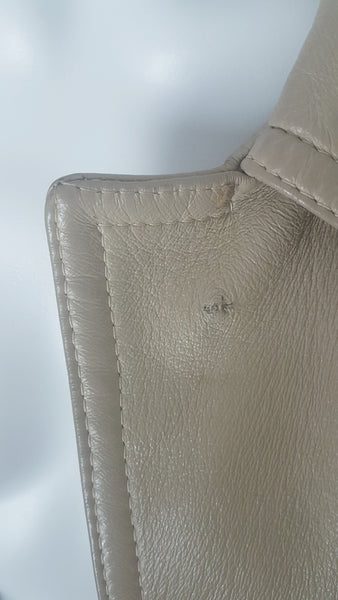 Faint dark mark view on a vintage 1970s sand-coloured leather trench coat with tonal buttons, shoulder tabs and a matching belt displayed on a mannequin