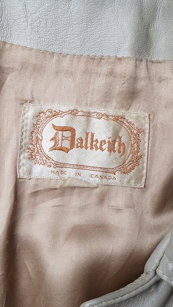 Dalkeith label on flatlay view of a vintage 1970s sand-coloured leather trench coat with tonal buttons, shoulder tabs and a matching belt