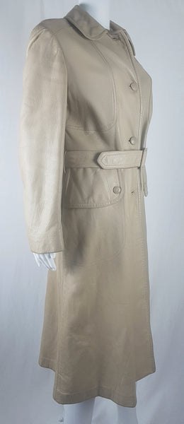 three-quarter view of a vintage 1970s sand-coloured leather trench coat with tonal buttons, shoulder tabs and a matching belt displayed on a mannequin