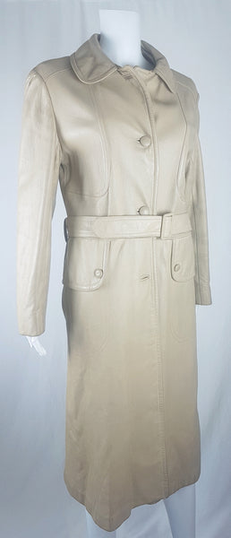 Side three-quarter view of a vintage 1970s sand-coloured leather trench coat with tonal buttons, shoulder tabs and a matching belt displayed on a mannequin