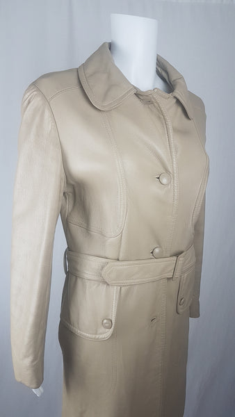Top three-quarter view of a vintage 1970s sand-coloured leather trench coat with tonal buttons, shoulder tabs and a matching belt displayed on a mannequin