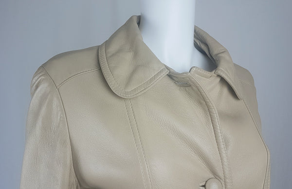 Shoulder and collar view of a vintage 1970s sand-coloured leather trench coat with tonal buttons, shoulder tabs and a matching belt displayed on a mannequin