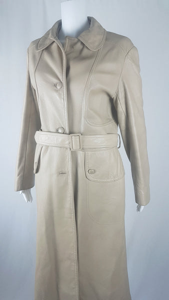 front view of a vintage 1970s sand-coloured leather trench coat with tonal buttons, shoulder tabs and a matching belt displayed on a mannequin