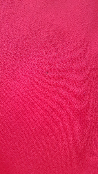 Fabric close up to show 2 small penmarks on a vintage 1970s Kenny Classics Donnkenny orange-red mod dress 